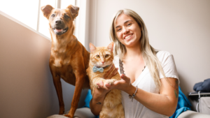 A cheerful dog walker in Columbus with a contented dog and cat.