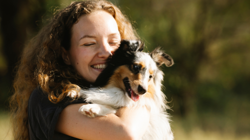 Happy pet sitter in Columbus hugging a dog and loving her job.